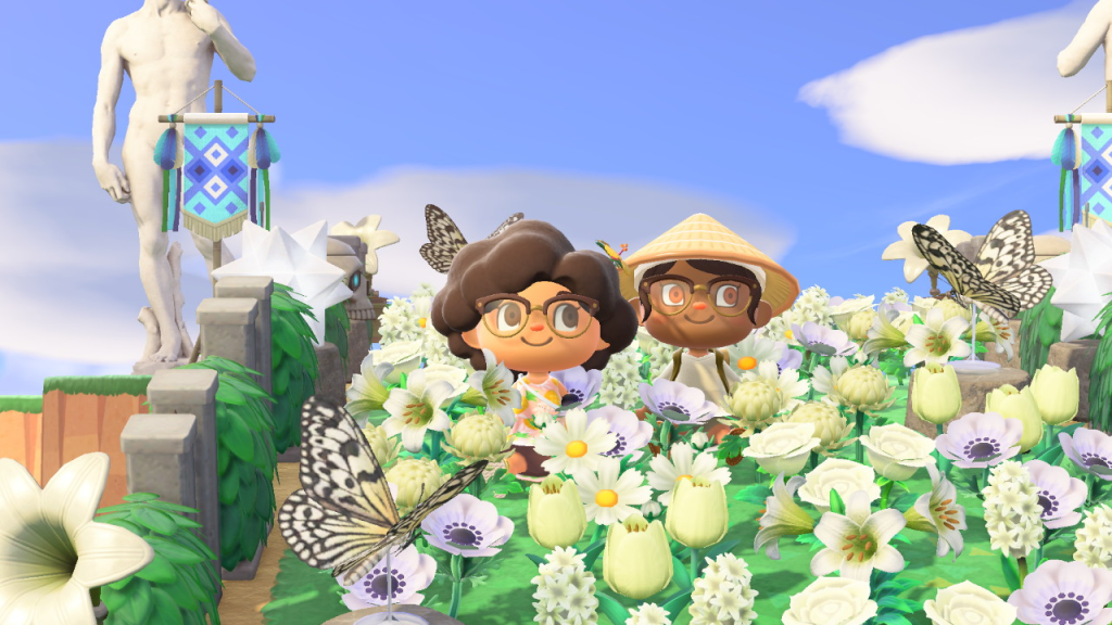 A screenshot of two Animal Crossing: New Horizons players, sitting in a field of white flowers and butterflies